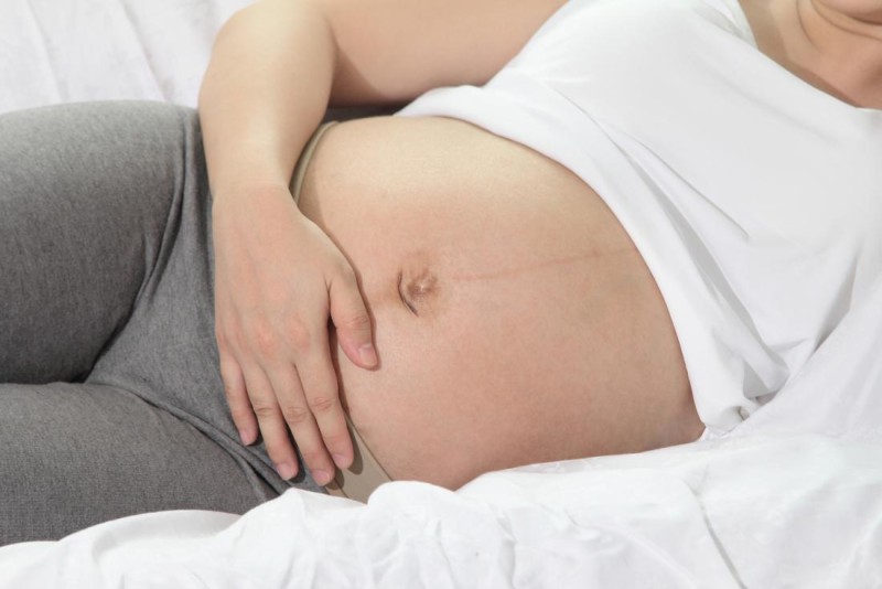 b2ap3 large pregnant person lying on side holding bump because of belly button pain