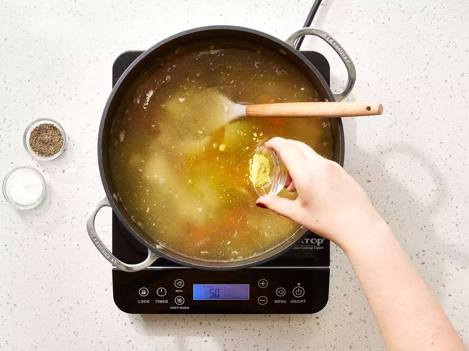 چاشنی به سوپ مرغ خانگی اضافه می شود.