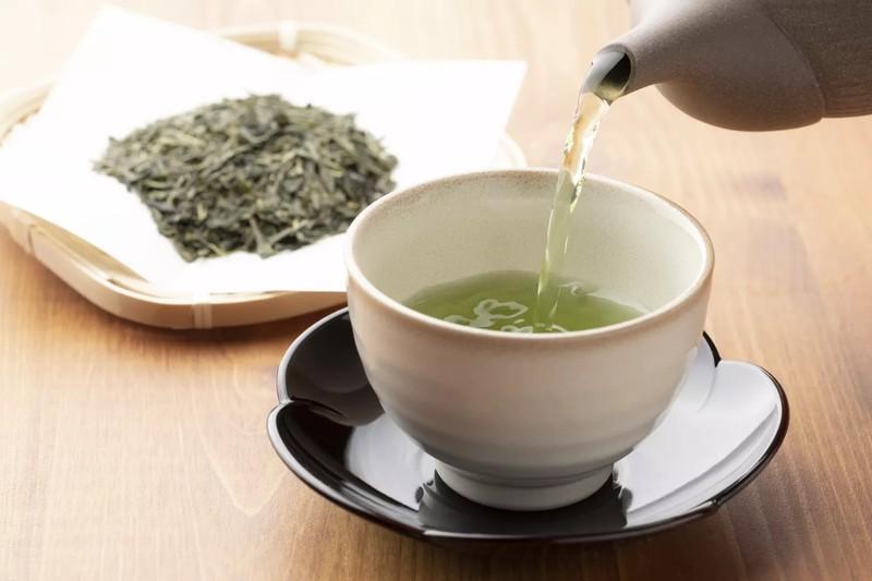 دمنوش ضد التهاب چای سبز گرم روی میز چوبی.