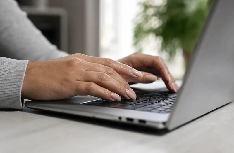Woman typing on a laptop keyboard with coffin-shaped manicured nails, مدل ناخن بادامی و تابوتی